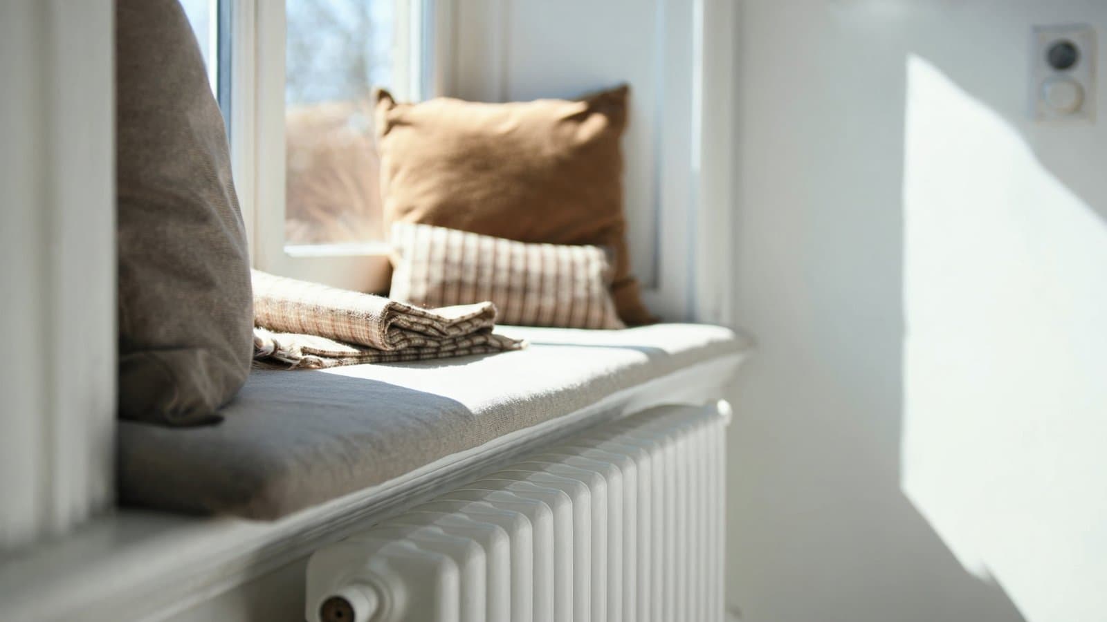 Een zonnige vensterbank met kussens boven een radiator